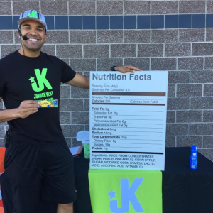 Coach at a youth sports camp teaching nutrition concepts using a nutrition facts sign during an outdoor camp session.